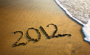 2012 written in the sand on a beach with an incoming wave.