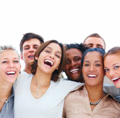 A group of diverse and joyful friends huddled together, smiling at the camera.