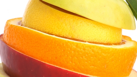 Slices of fruit arranged in a stack with an apple at the bottom, an orange in the middle, and a banana on top.