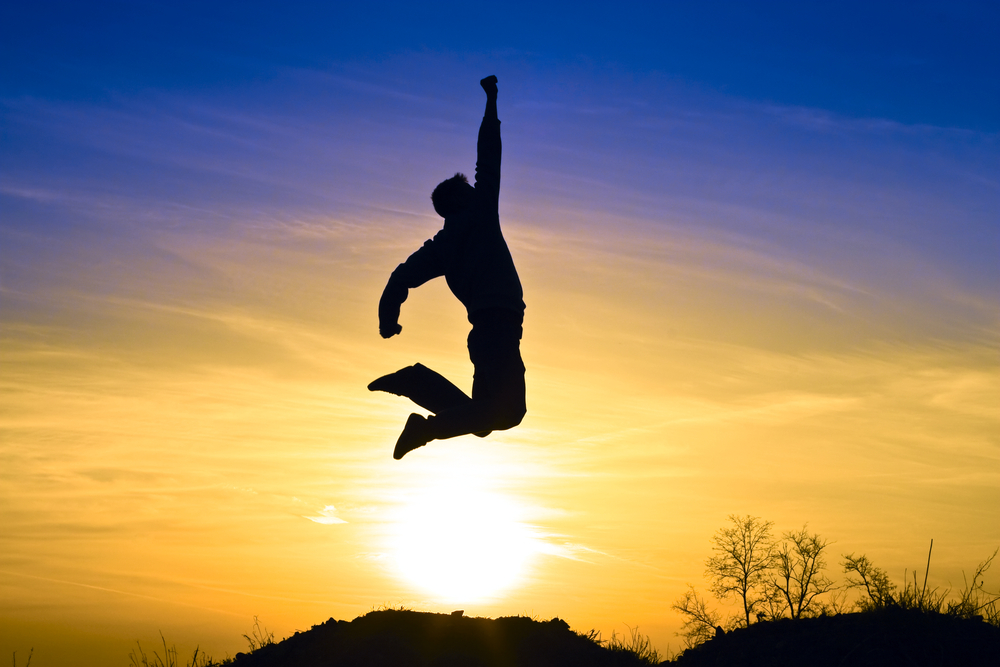 Person jumping against a sunset sky.