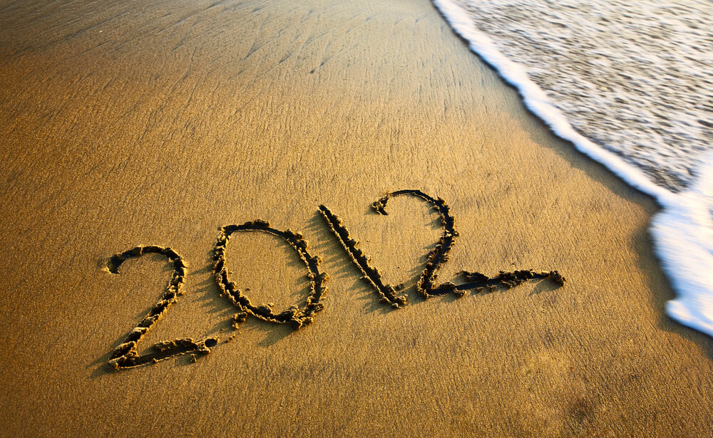 2012 written in the sand on a beach with an incoming wave.