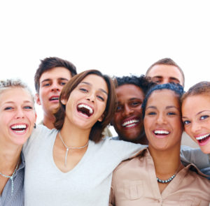 A diverse group of people smiling and posing closely together for a group photo.