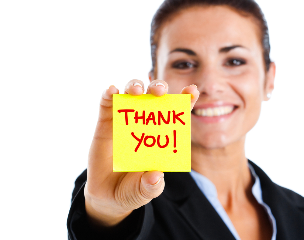 image of a woman holding a thank you post it note