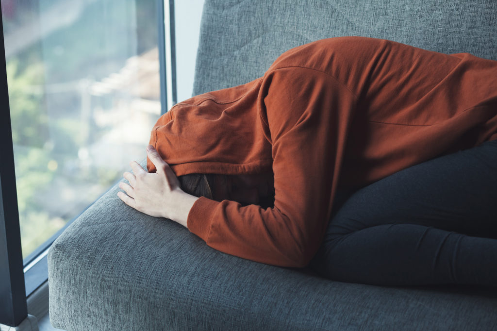 mental health, stress, migraine or depression concept, young sad depressed frustrated woman sitting at home alone suffering and crying