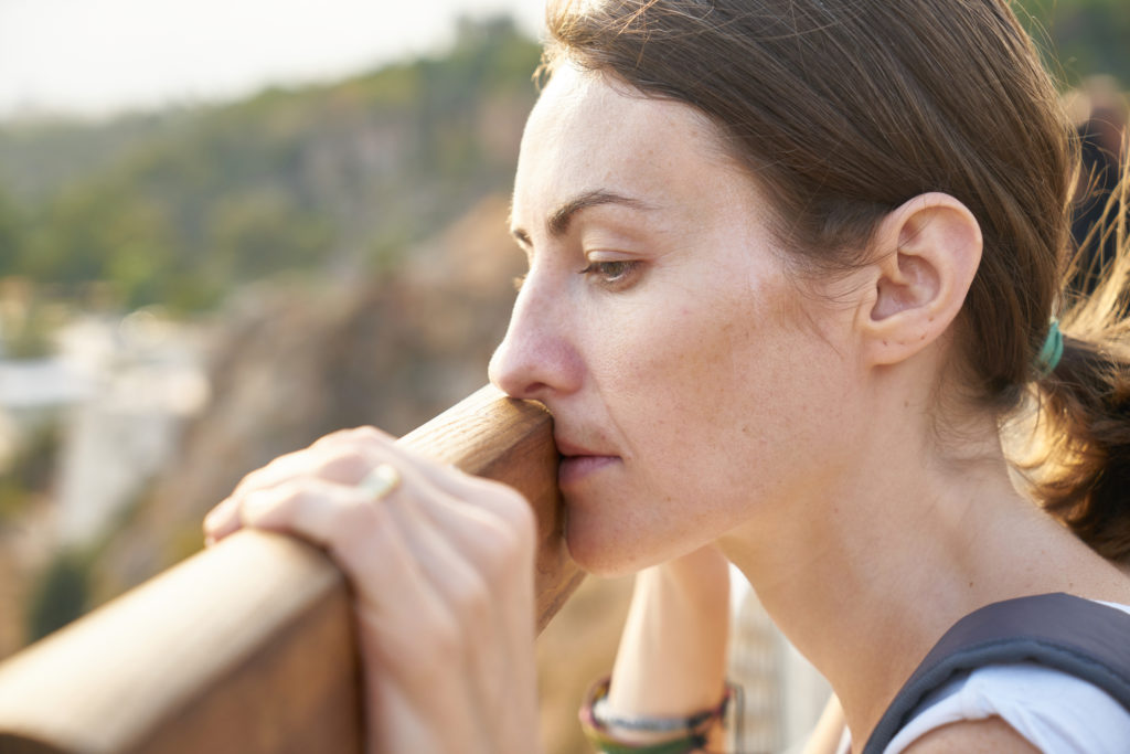 Woman gazing into the distance with her chin resting on her hands.