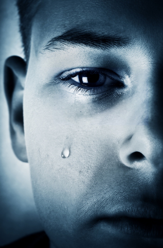 Close-up of a child's face with a tear rolling down the cheek.