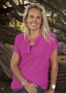Woman in a pink blouse smiling outdoors.