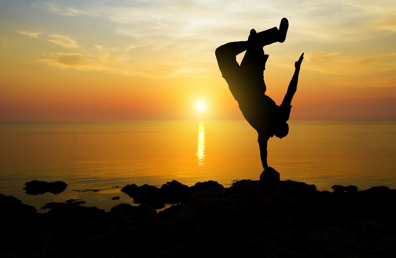 silhouette of a man doing handstand during sunset at the beach