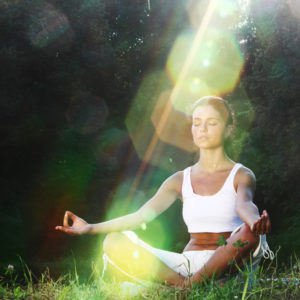 image of woman meditating on grass
