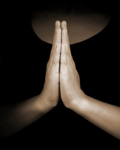 woman standing with hands in prayer position 