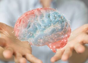 How Does Brainspotting Work A person holds out their hands with a digital rendering of a human brain floating above them, highlighting neural connections with light points.